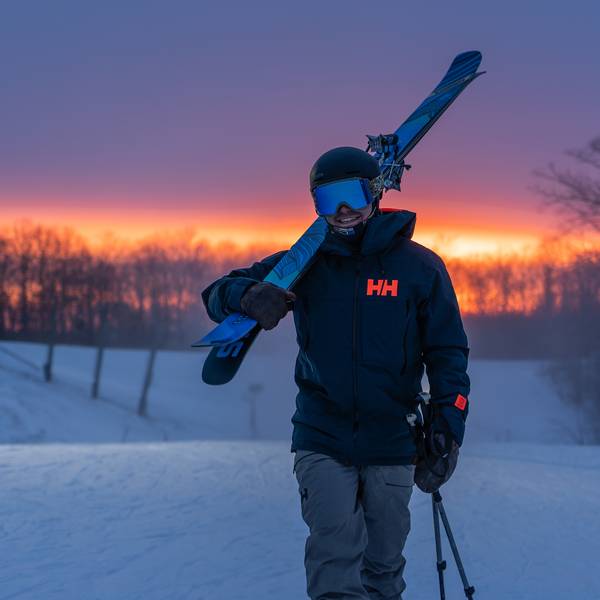 Man carrying skis at night.