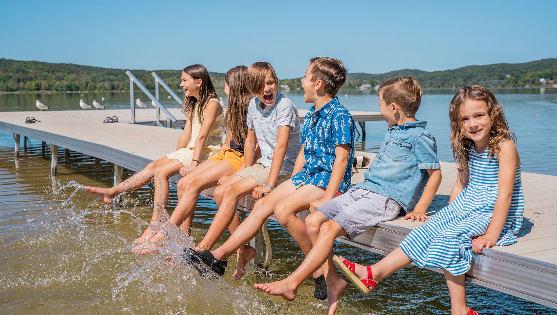 Children splashing feet in deer lake on the dock