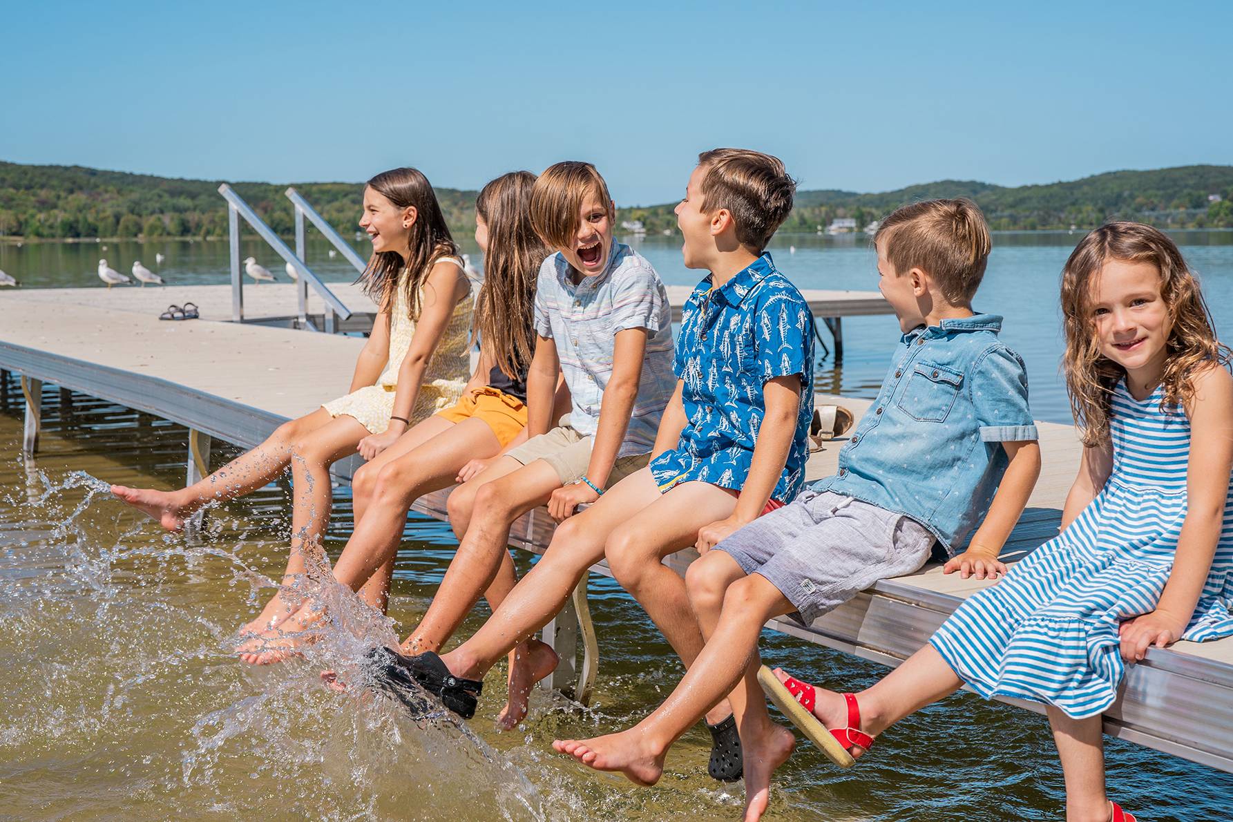 Children splashing feet in deer lake on the dock