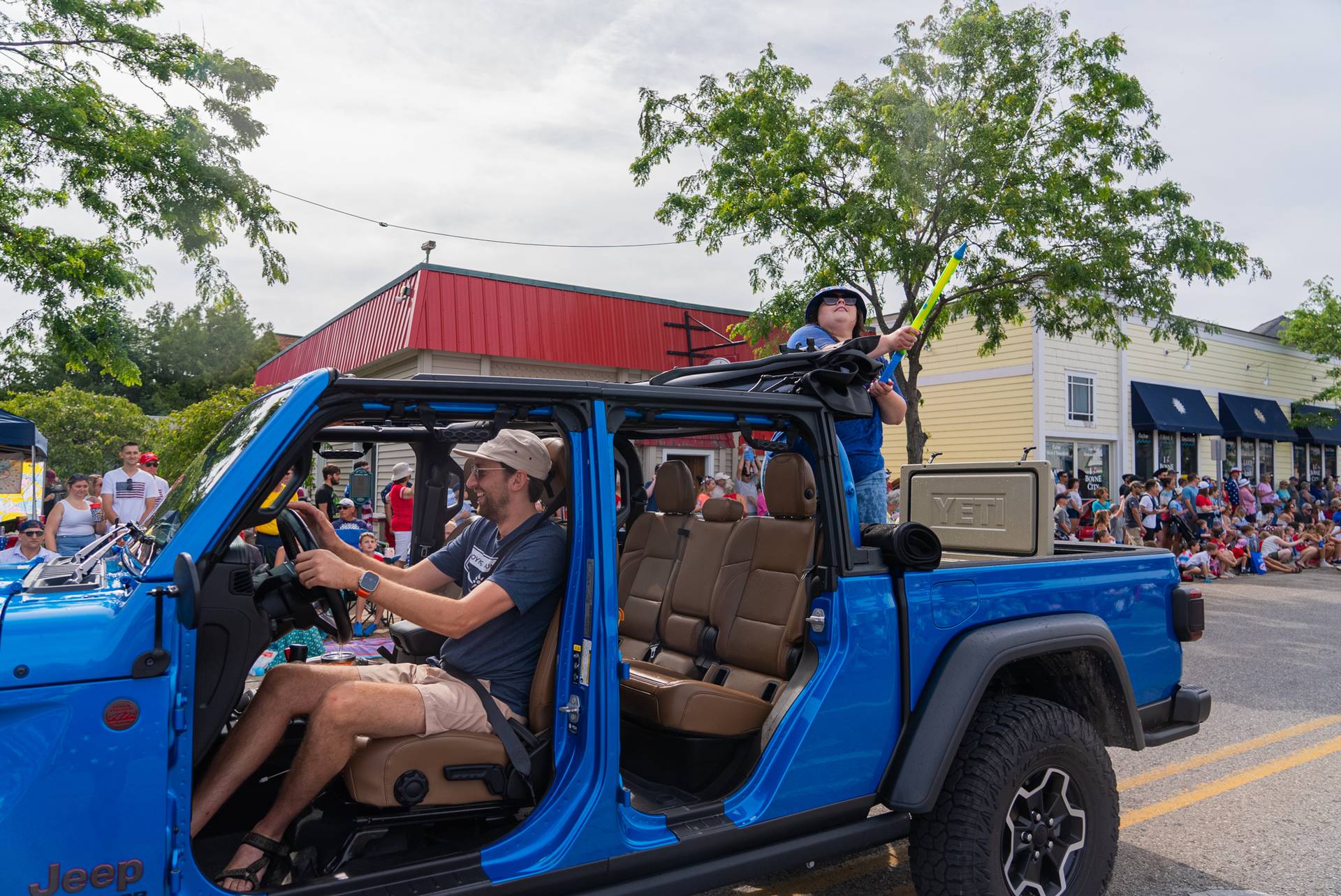 Truck driving in parade with people using water guns