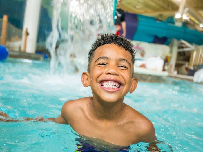 Young boy smiling while playing at Avalanche Bay Waterpark.