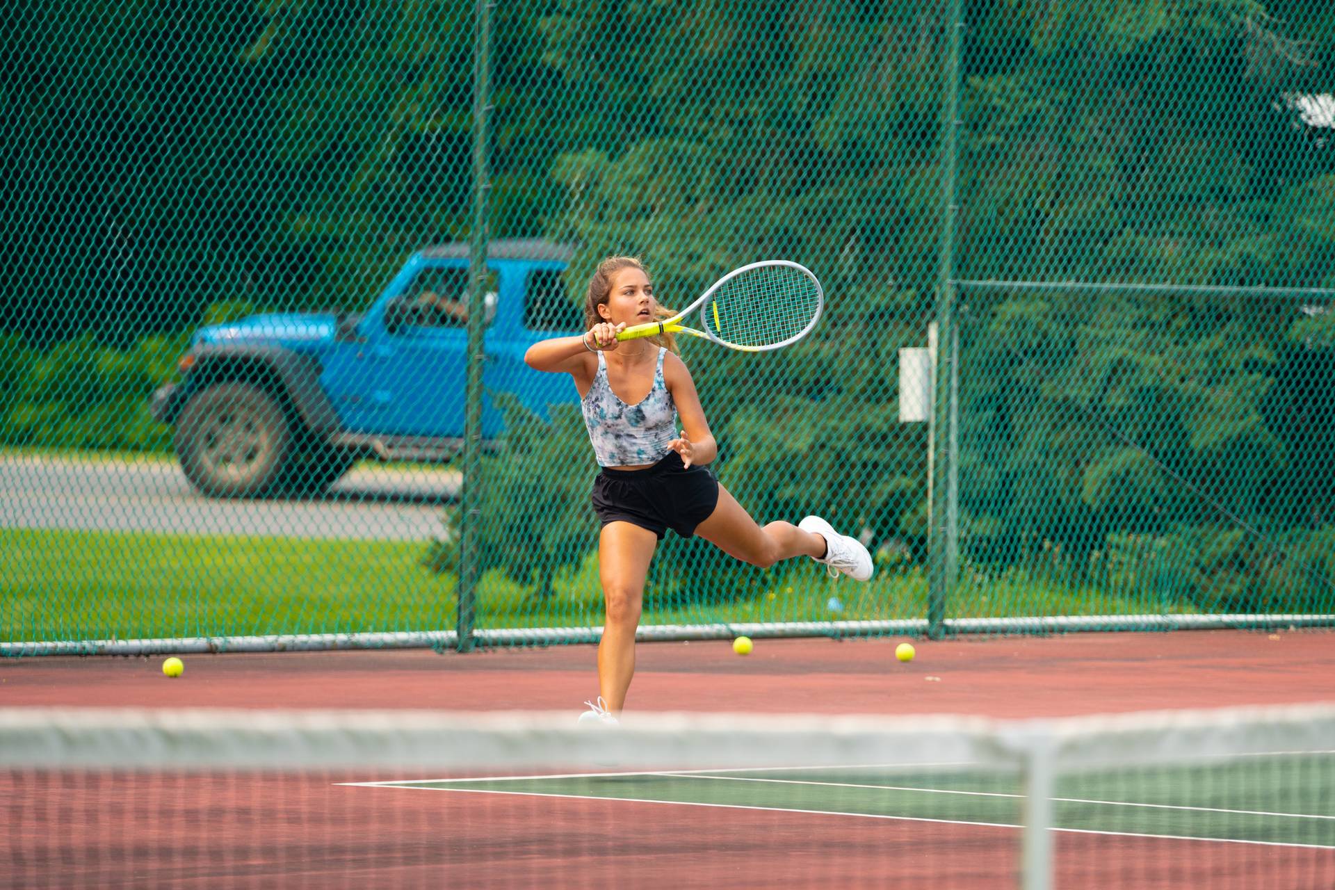 Girl running hard to hit tennis ball.