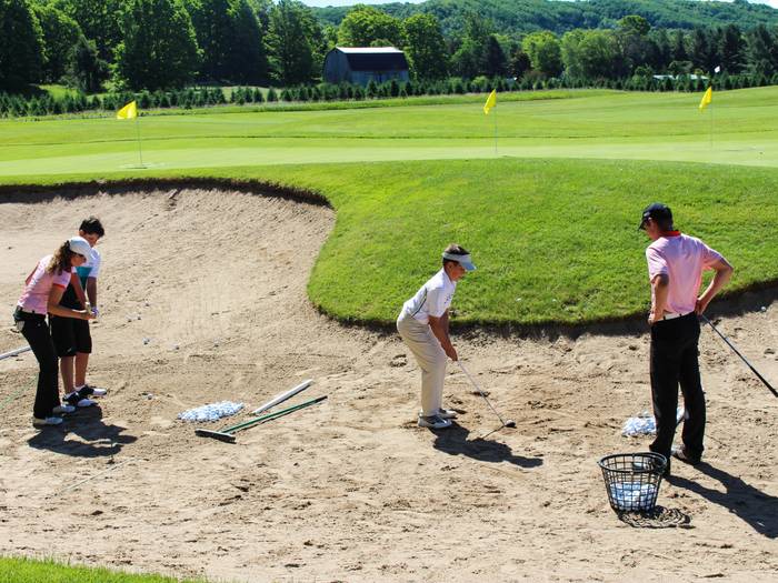 Kid's taking instruction from golf pros