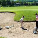 Two boys receiving golf instruction