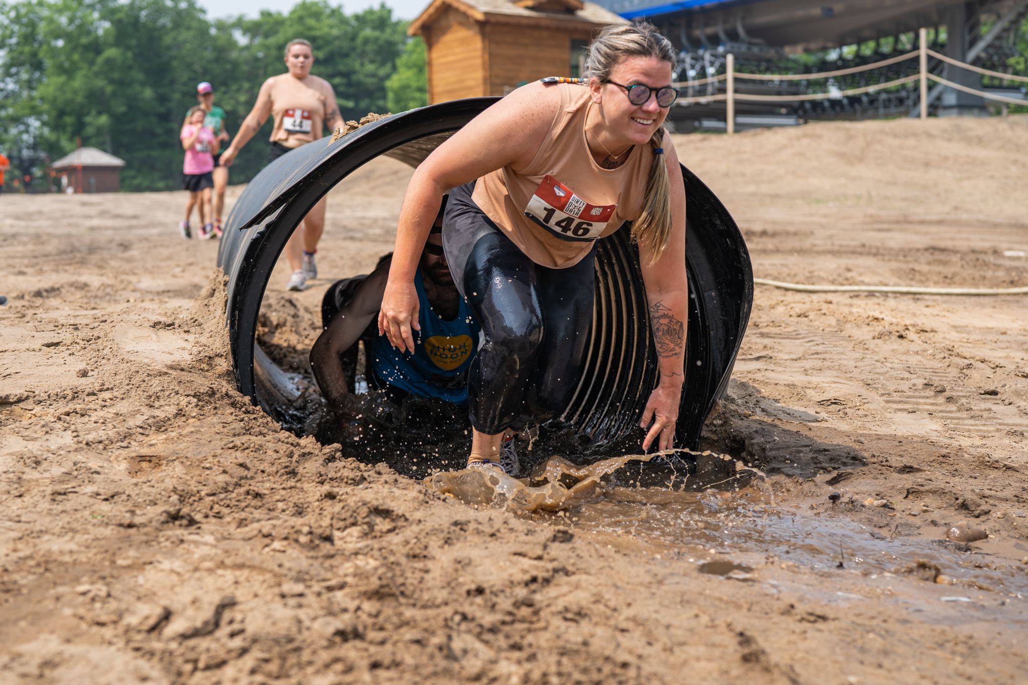 Girl racer climbing out of mud tunnel obstacle