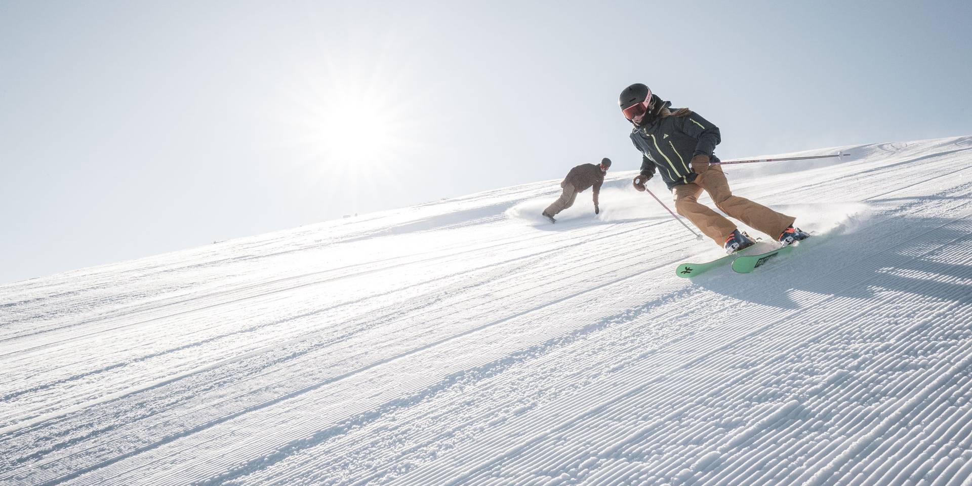 Skier and snowboarder on a groomed run