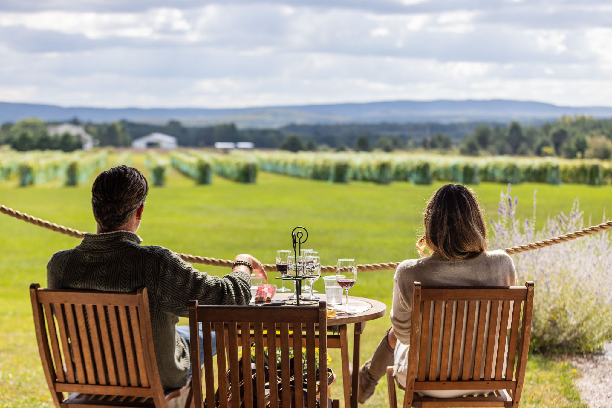 Couple sitting down at winery looking over vineyards.