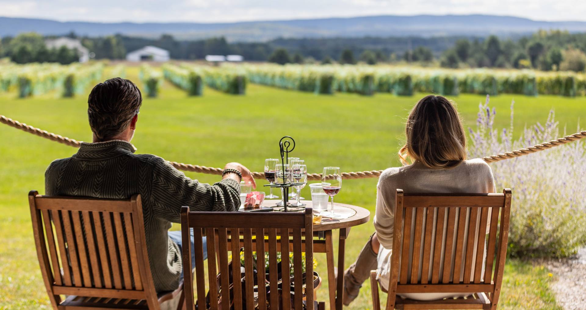 Couple sitting down at winery looking over vineyards.