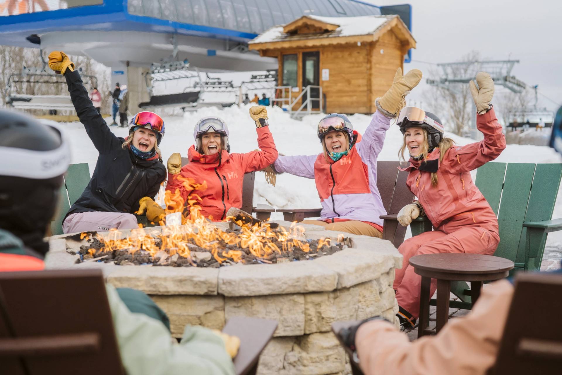 Ladies sitting around a fire at the top of SkyBridge Michigan in their ski gear