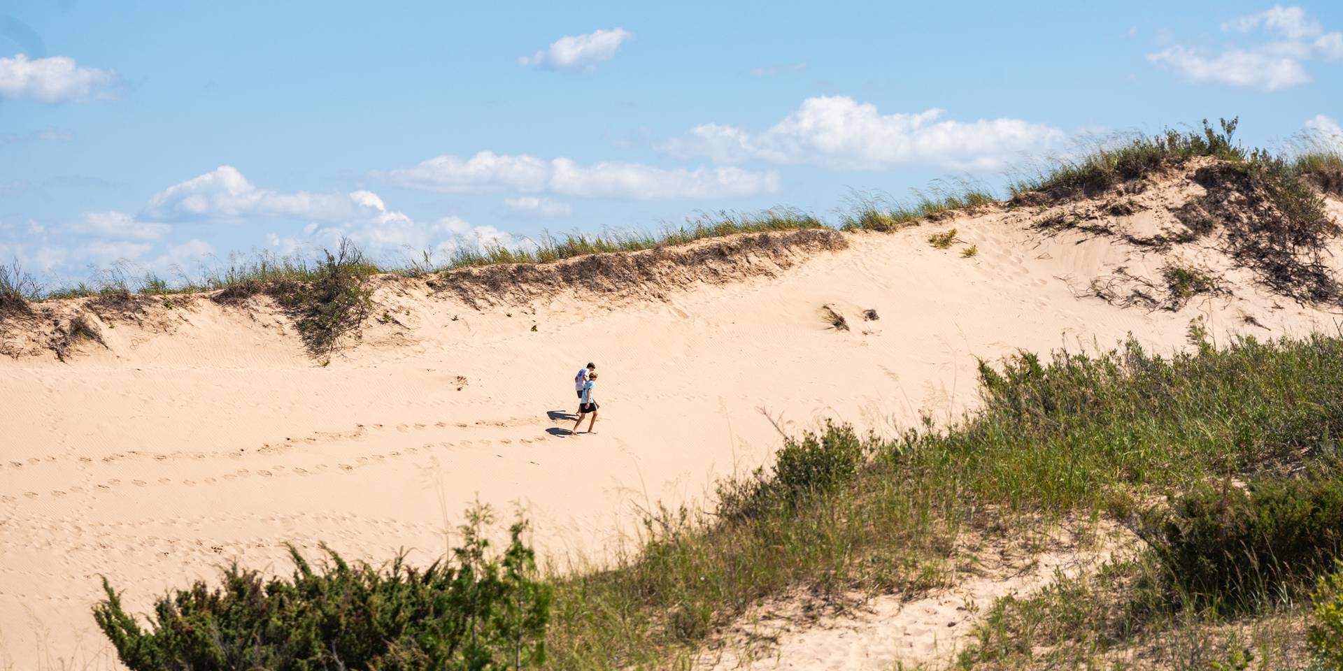 two people hiking on a sand dune