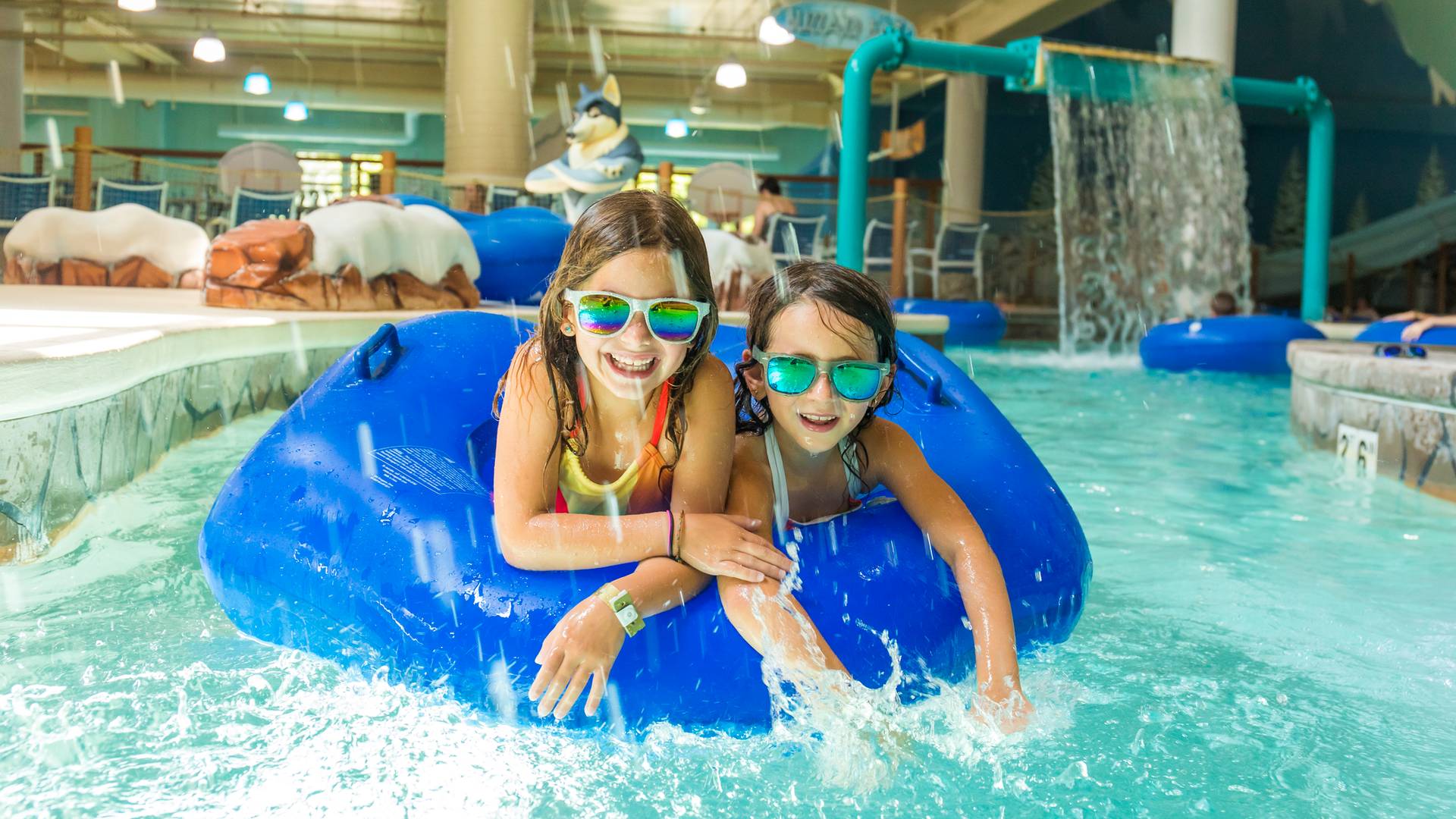 Two kids riding in a tube down the lazy river at Avalanche Bay indoor waterpark