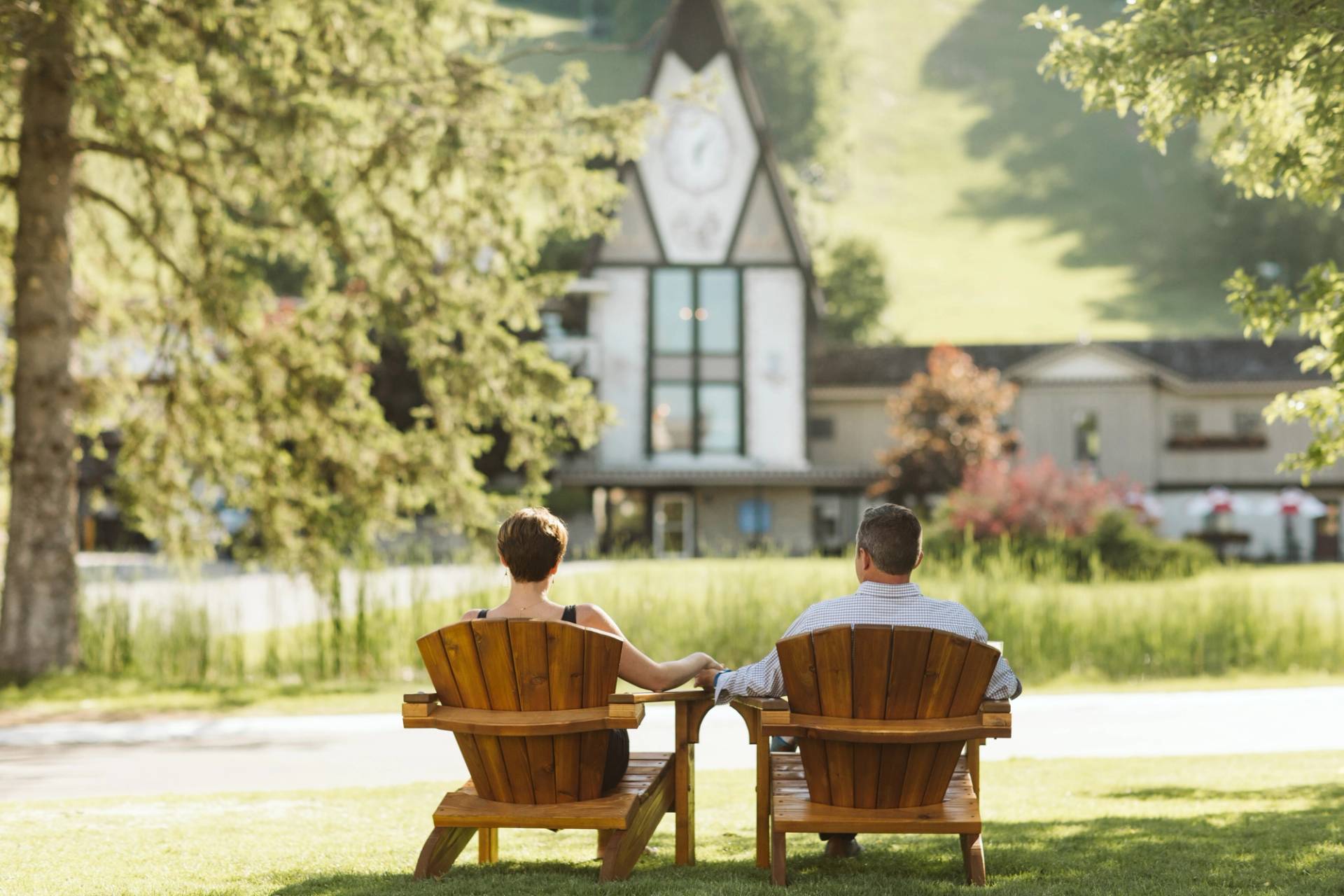 Couple holding hands in chairs front of Clock Tower Lodge