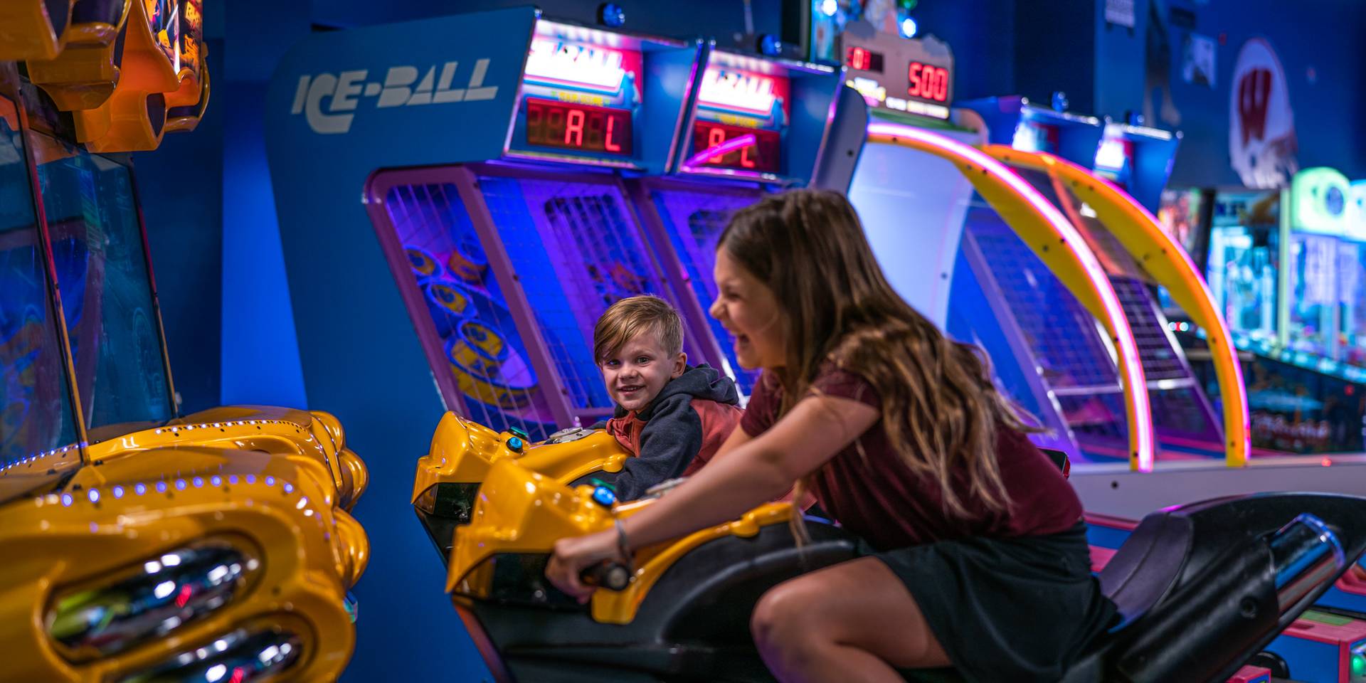 Two children both playing on the motorcycle game.