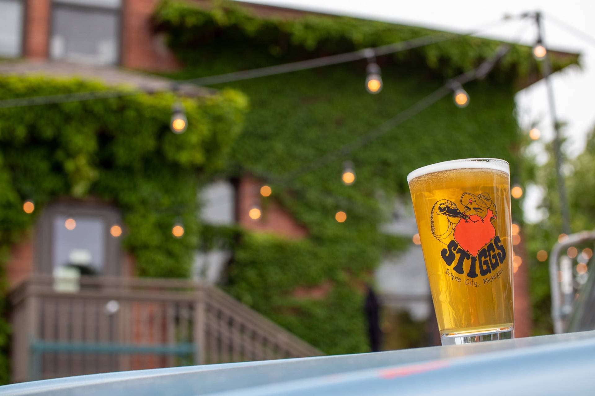 Glass of beer out front of Stiggs brewery with logo on glass