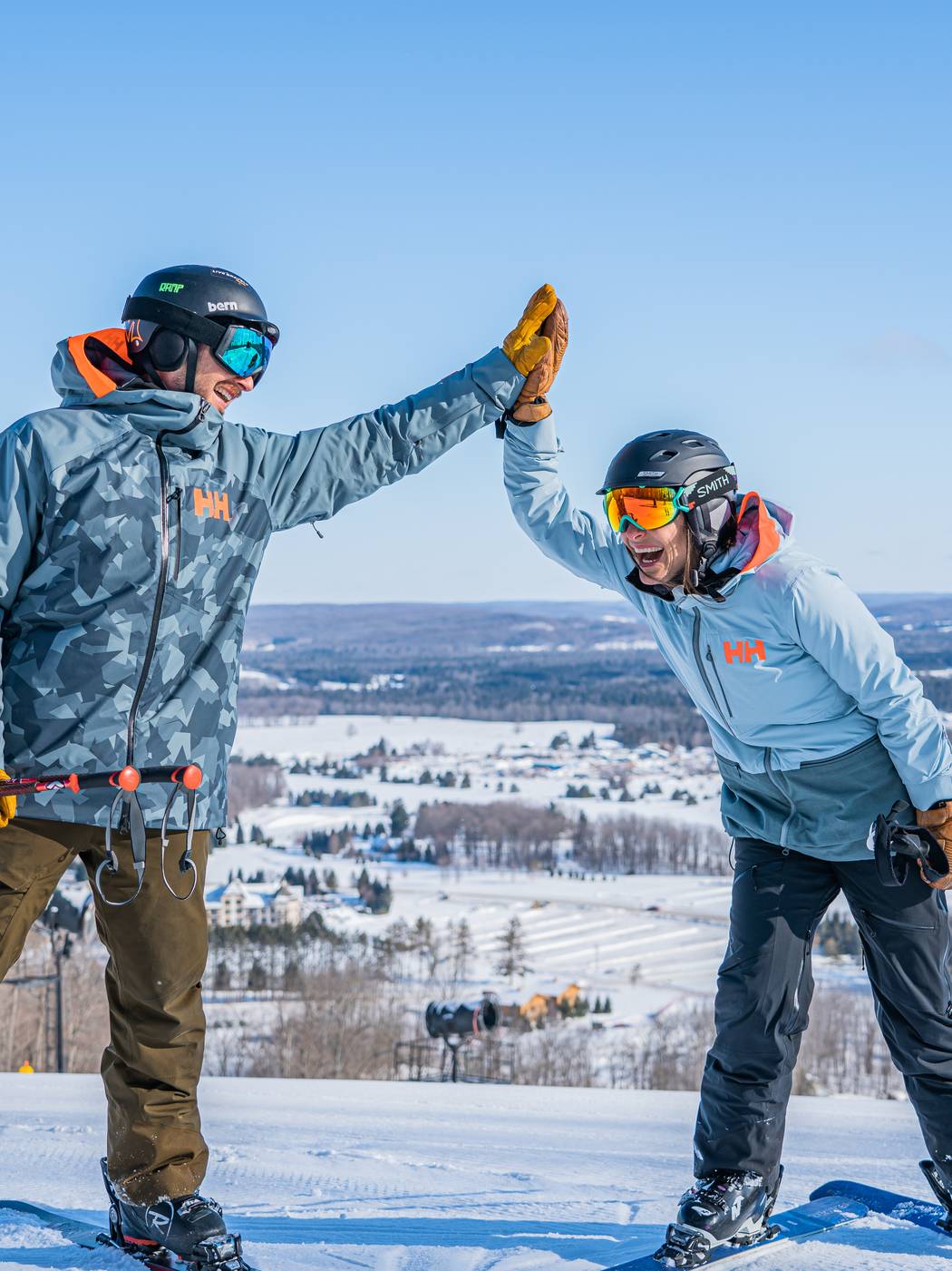 Skiing couple at the top of the mountain in winter high fiving