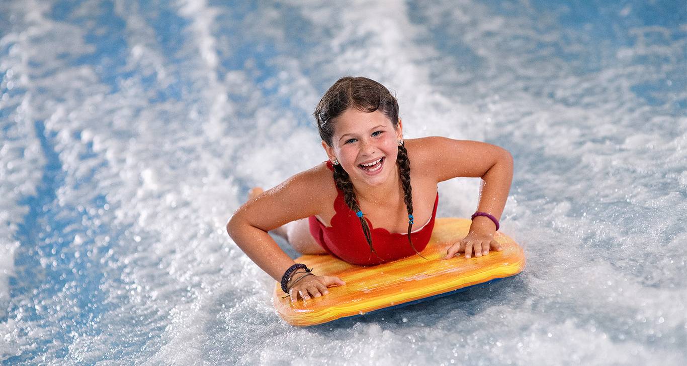 Girl boggie boarding on Surf Sumulator at waterpark