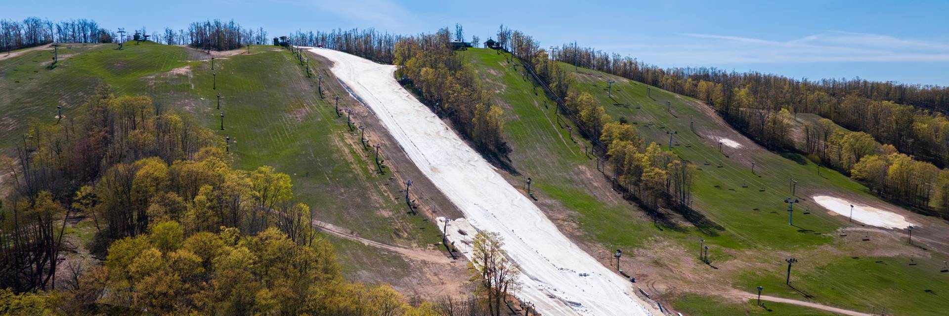 Drone shot of Victor Glacier with blue skies and green trees