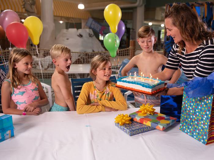 Mom holding cake at birthday party at waterpark