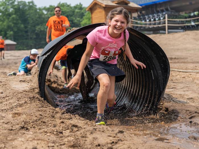 Girl going through mud tunnel obstacle