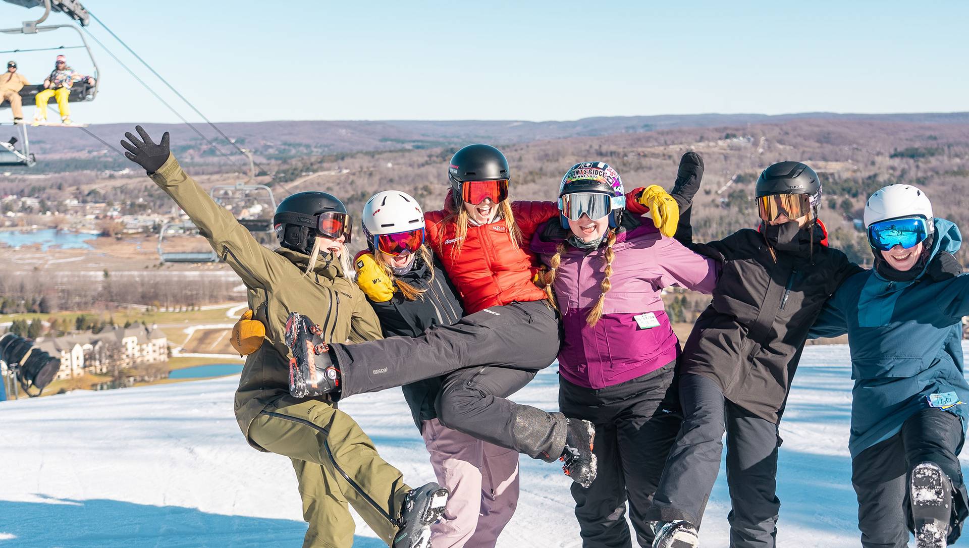 Five ladies in a group cheering and having so much fun on the slopes.