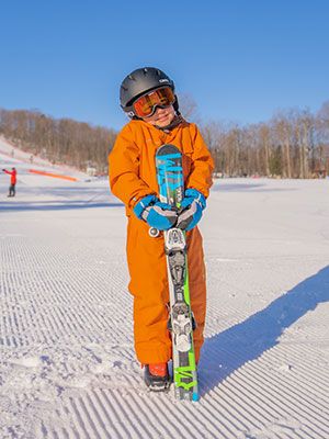 Boy posing for a picture on the bottom of the hill with his skis