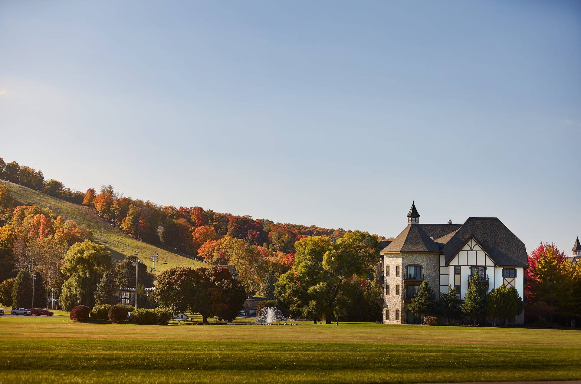 Sunset arial view of Mountain Grand Lodge and Spa with ski hills in the background.