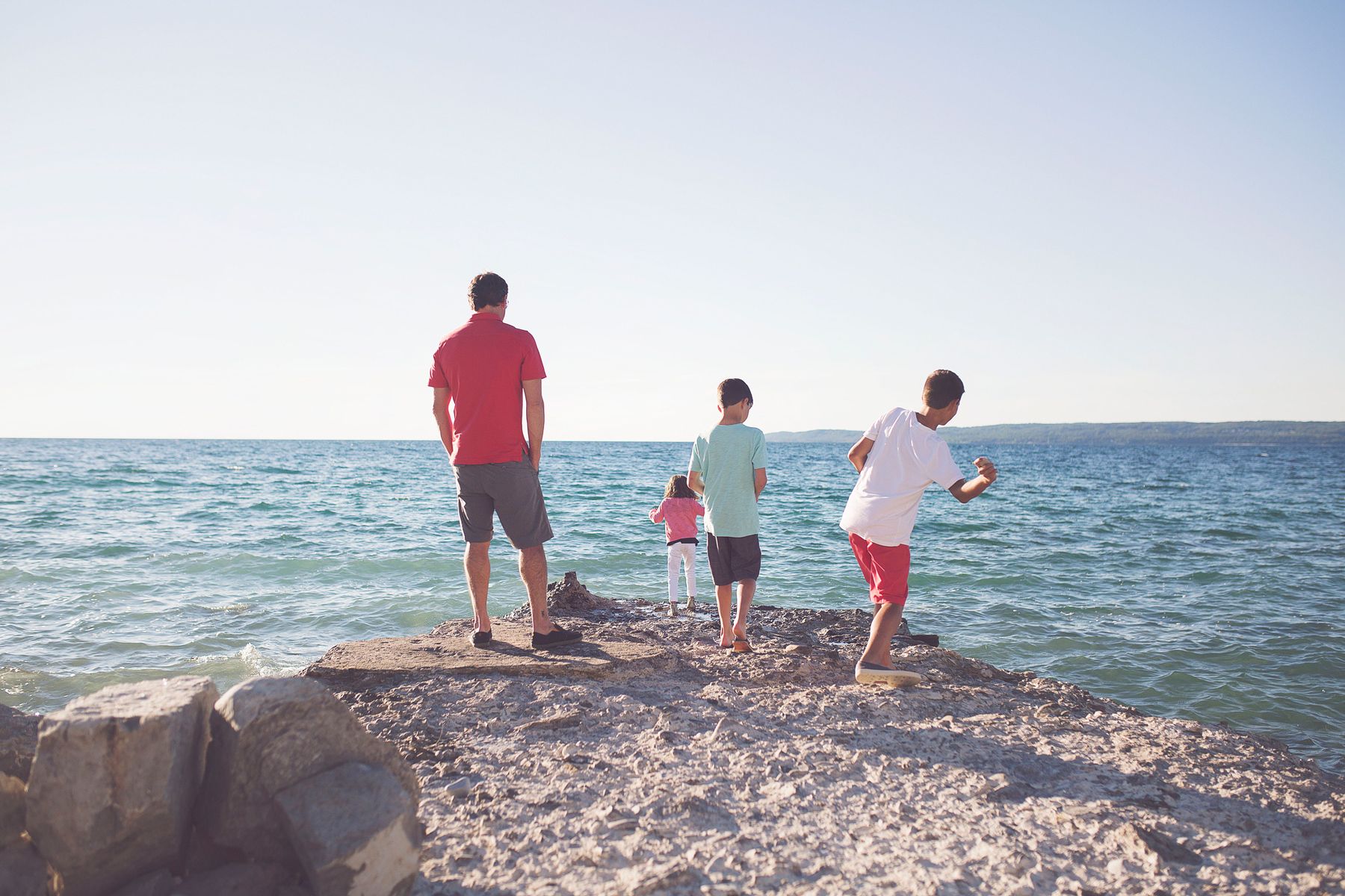 A family skips stones along the lakeshore