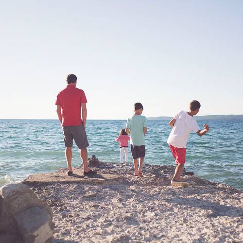 A family skips stones along the lakeshore