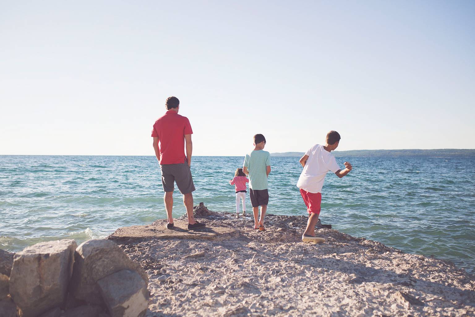A family skips stones along the lakeshore