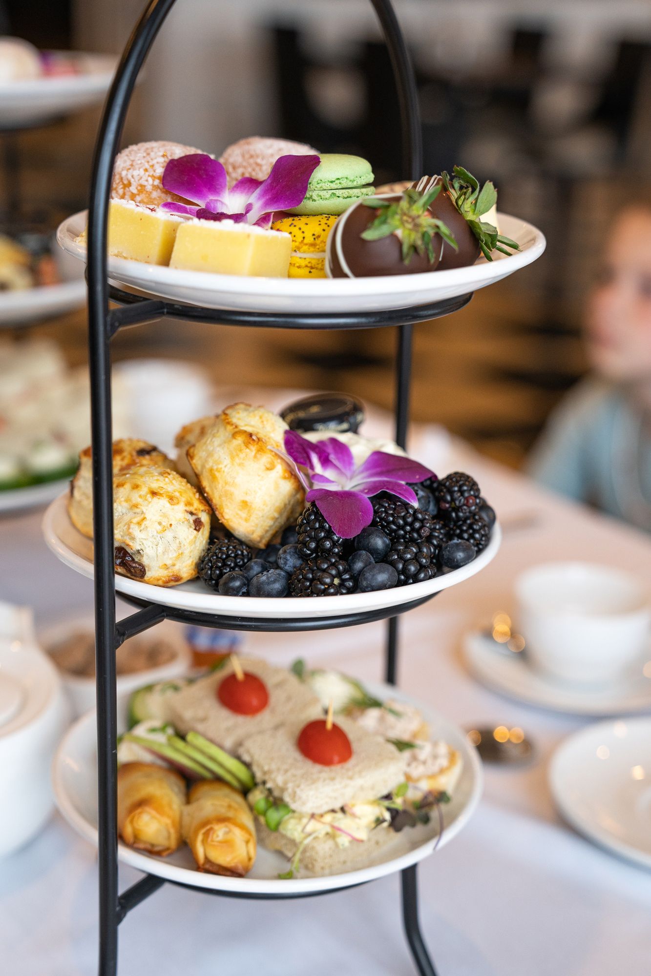 Colorful details of tiered Afternoon Tea tray with scones, berries, finger sandwiches