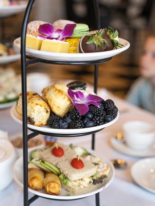 Colorful details of tiered Afternoon Tea tray with scones, berries, finger sandwiches