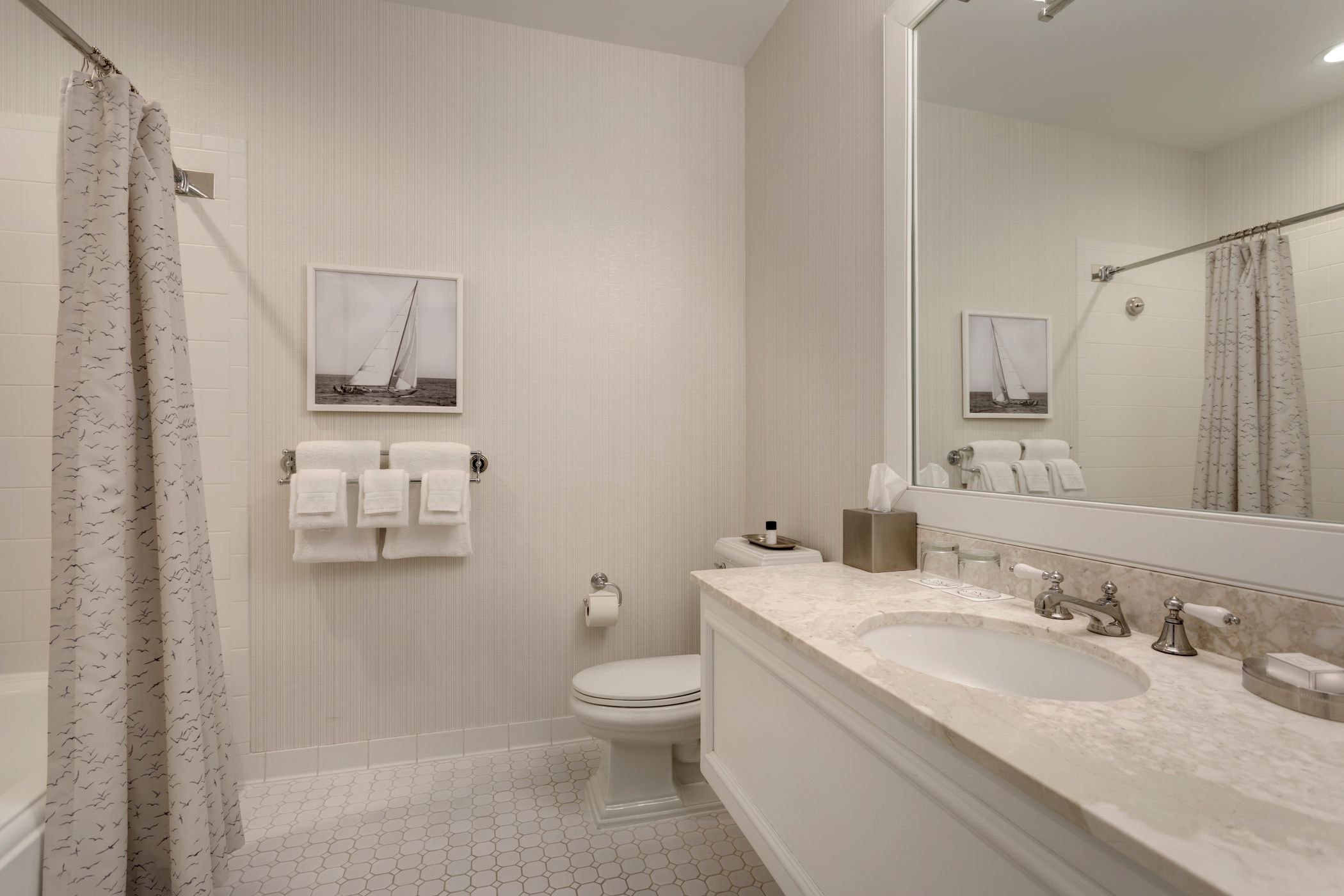 Hotel bathroom view of marble sink, mirror, toilet, and shower tub