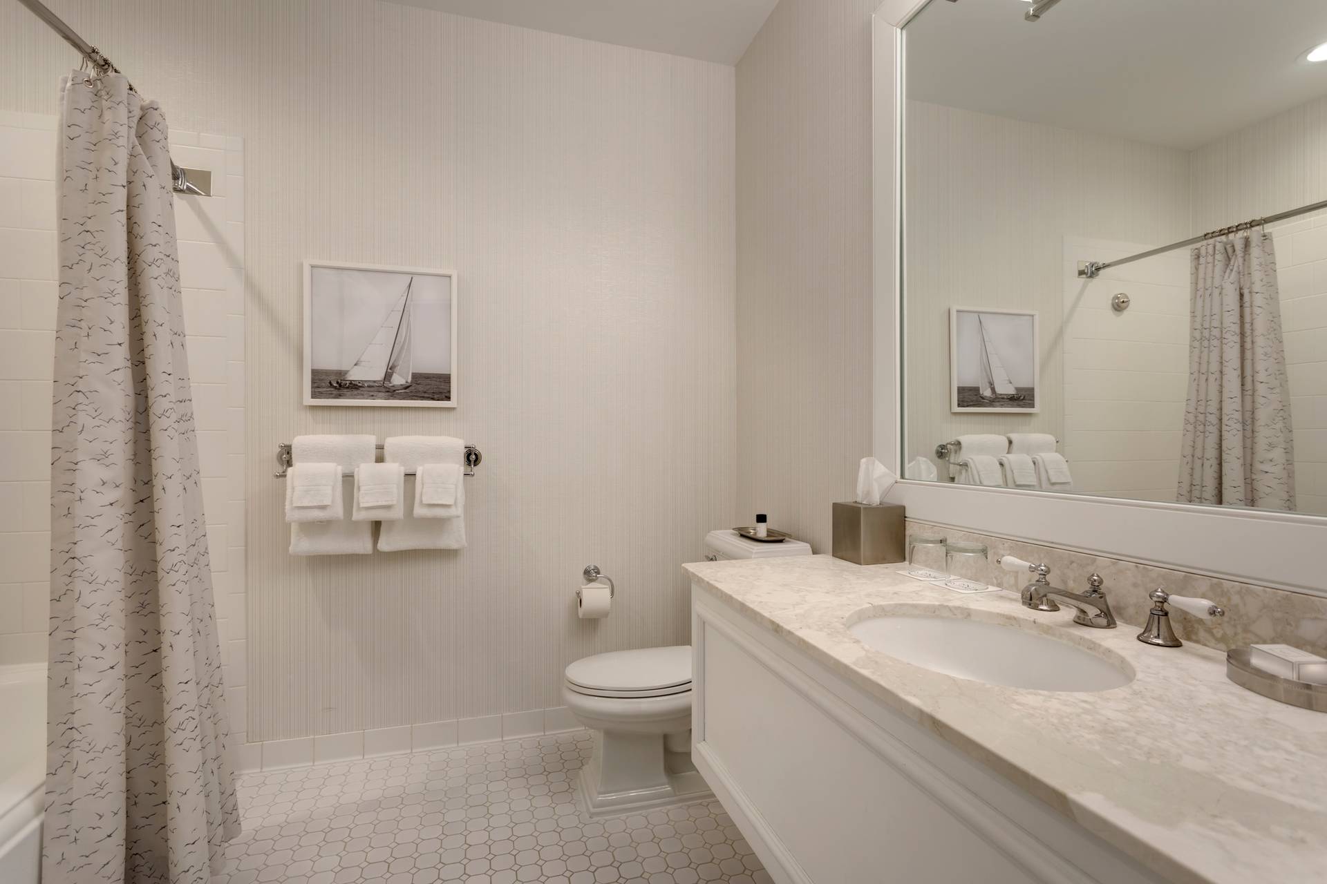 Hotel bathroom view of marble sink, mirror, toilet, and shower tub