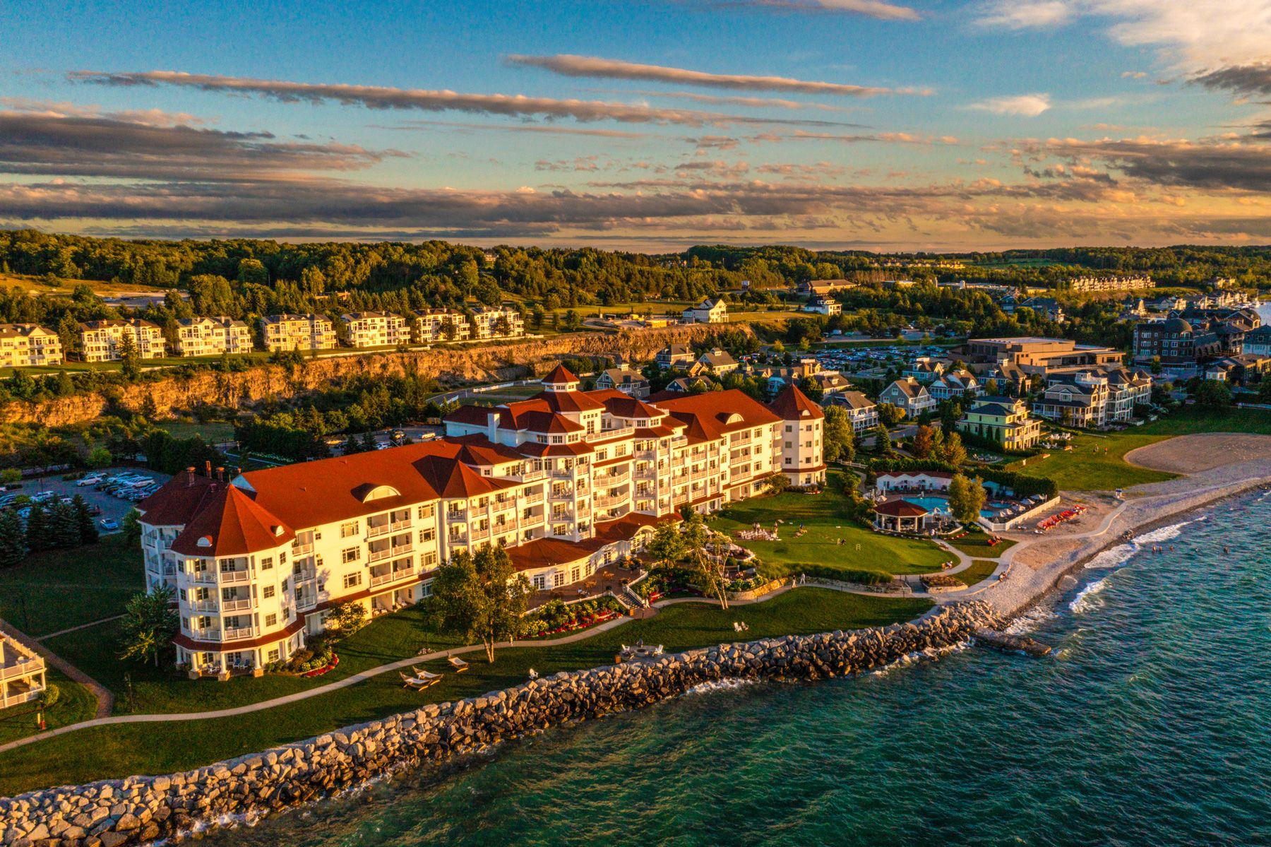 Aerial view of golden-tinted Inn at Bay Harbor hotel on Lake Michigan, with town background at sunset