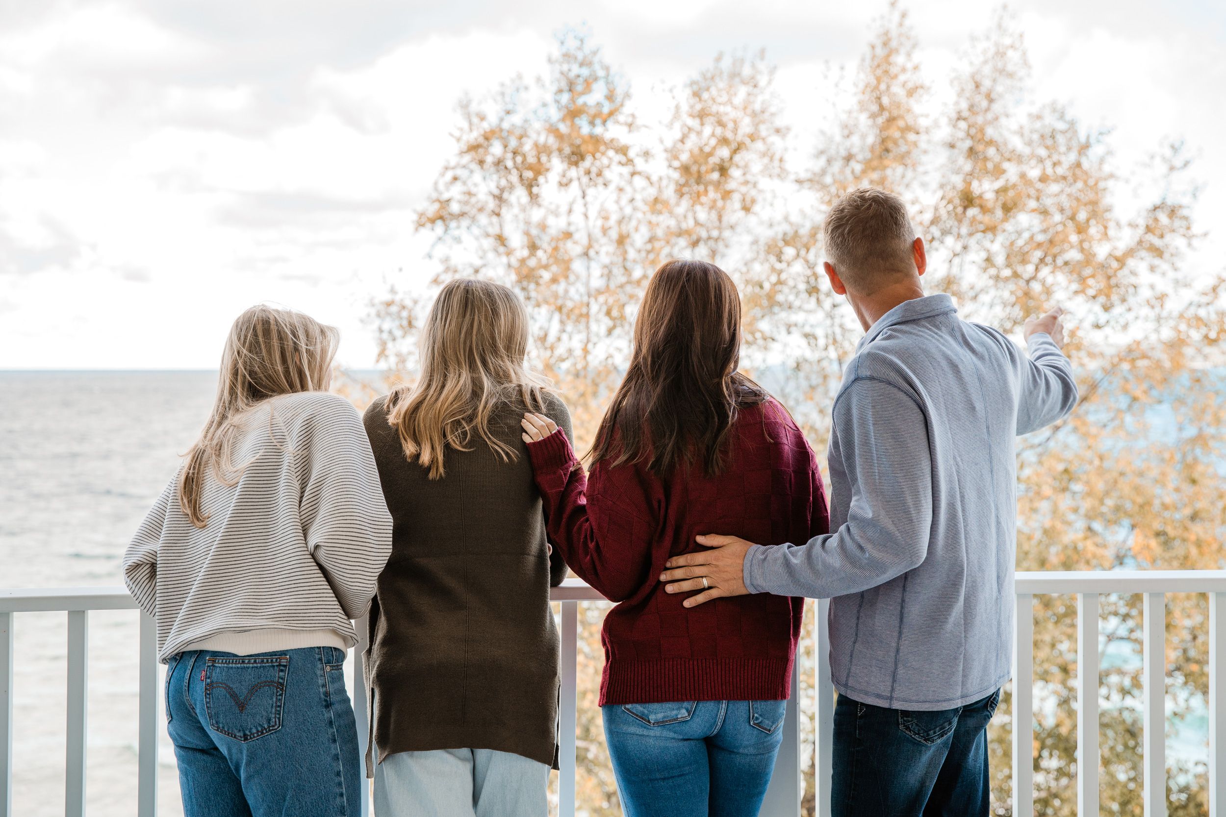 Family on fall balcony, pointing at water view, Inn at Bay Harbor