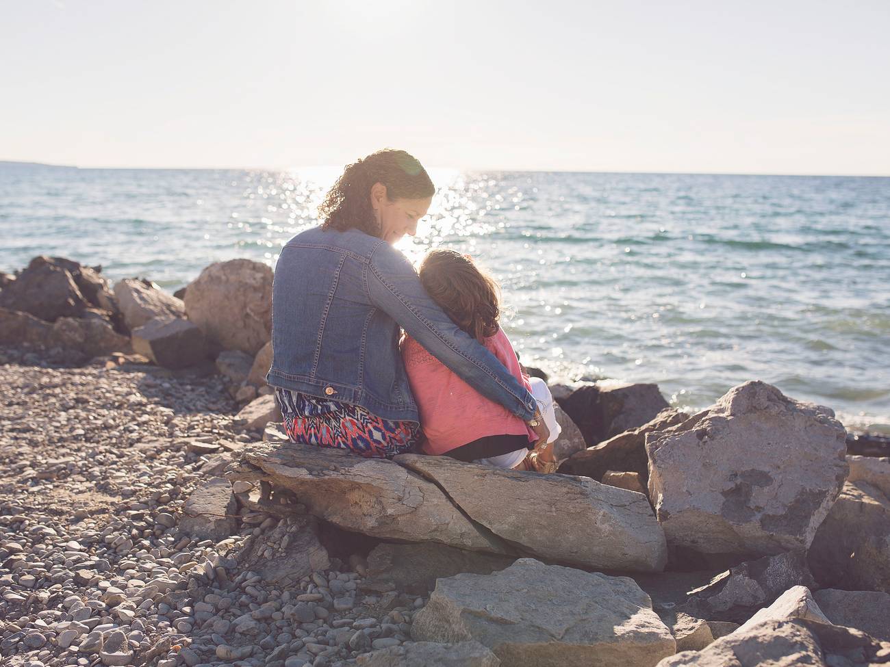 Mom and young daughter snuggle near Lake Michigan