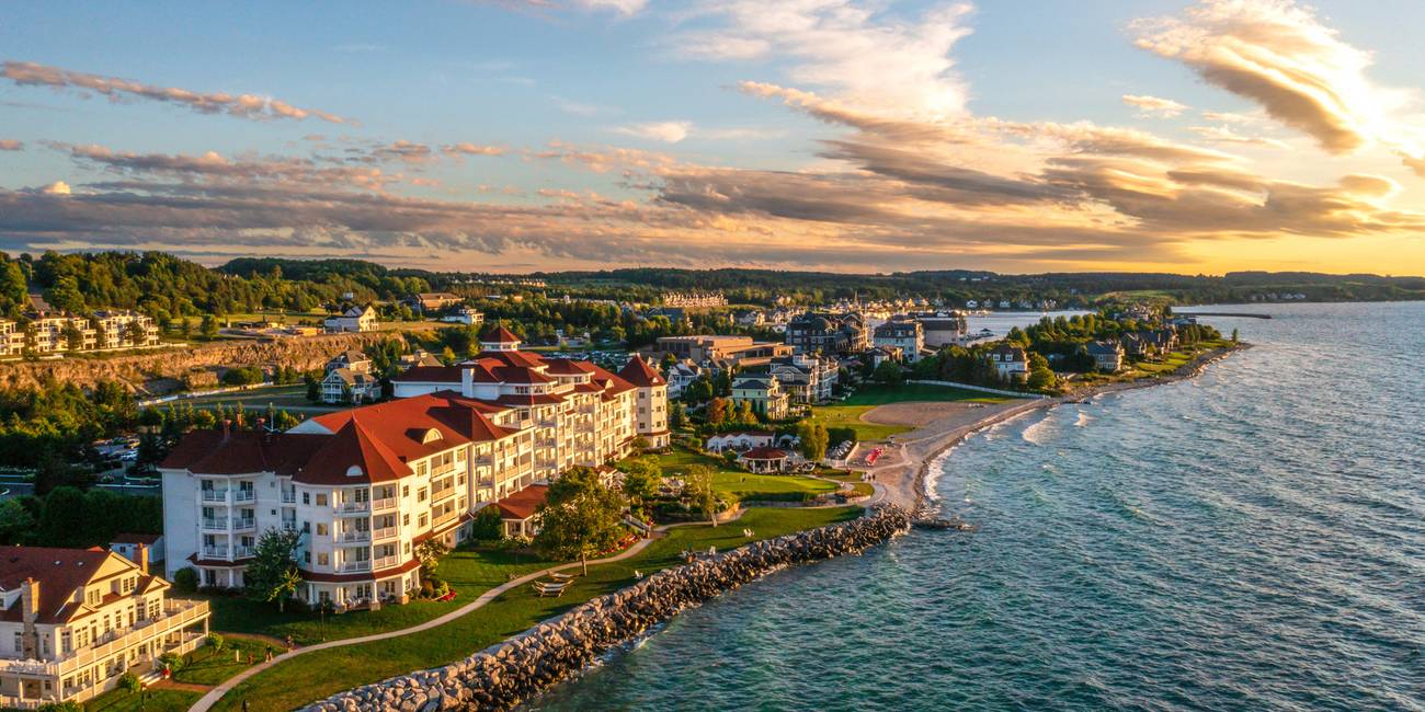 Side aerial exterior view of Inn at Bay Harbor, and Bay Harbor beyond under orange sunset sky