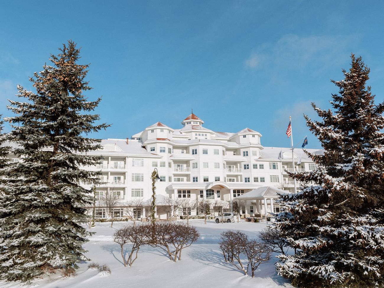 A winter exterior of the Inn at Bay Harbor framed in evergreens