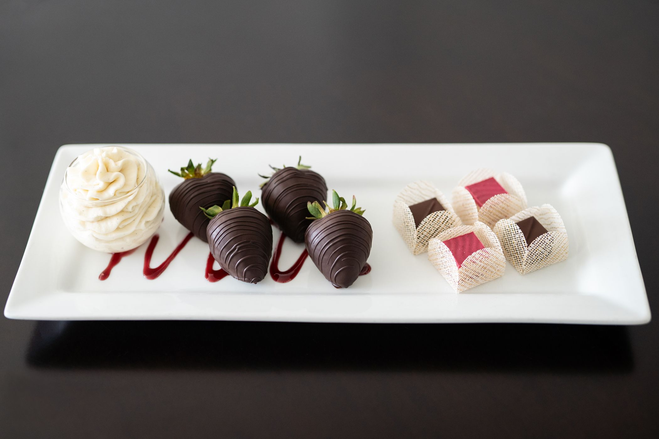 Tray with chocolate-covered strawberries, artisan truffles, and whipped cream