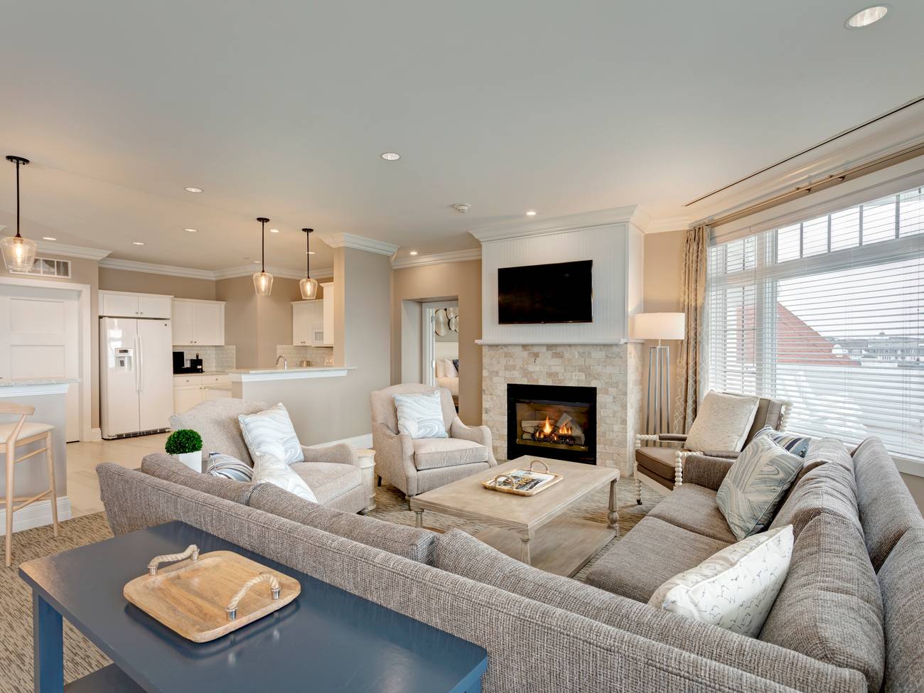 Inn at Bay Harbor Penthouse living area overview with sectional couch, chairs in front of fireplace, open from kitchen