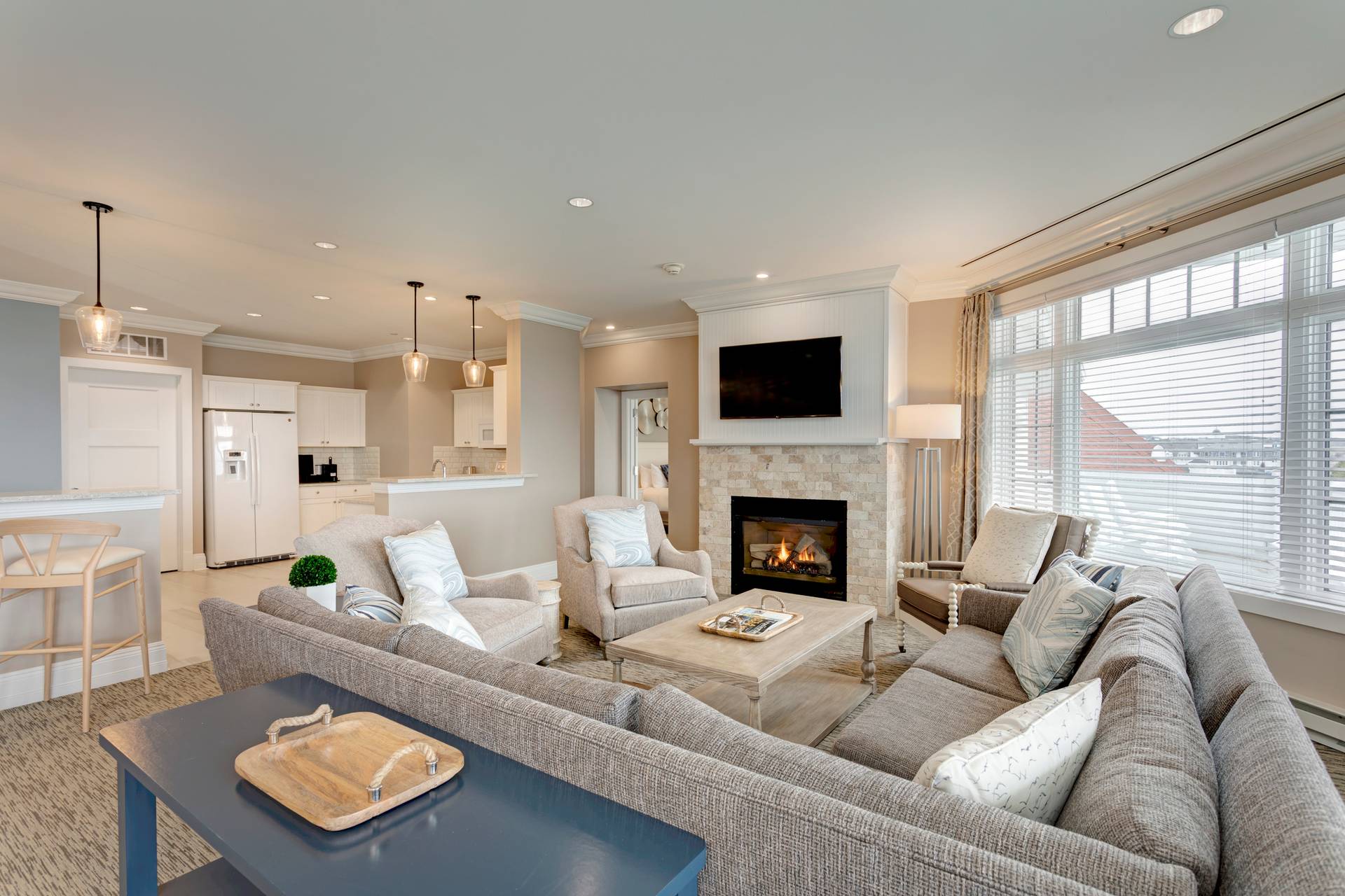 Inn at Bay Harbor Penthouse living area overview with sectional couch, chairs in front of fireplace, open from kitchen