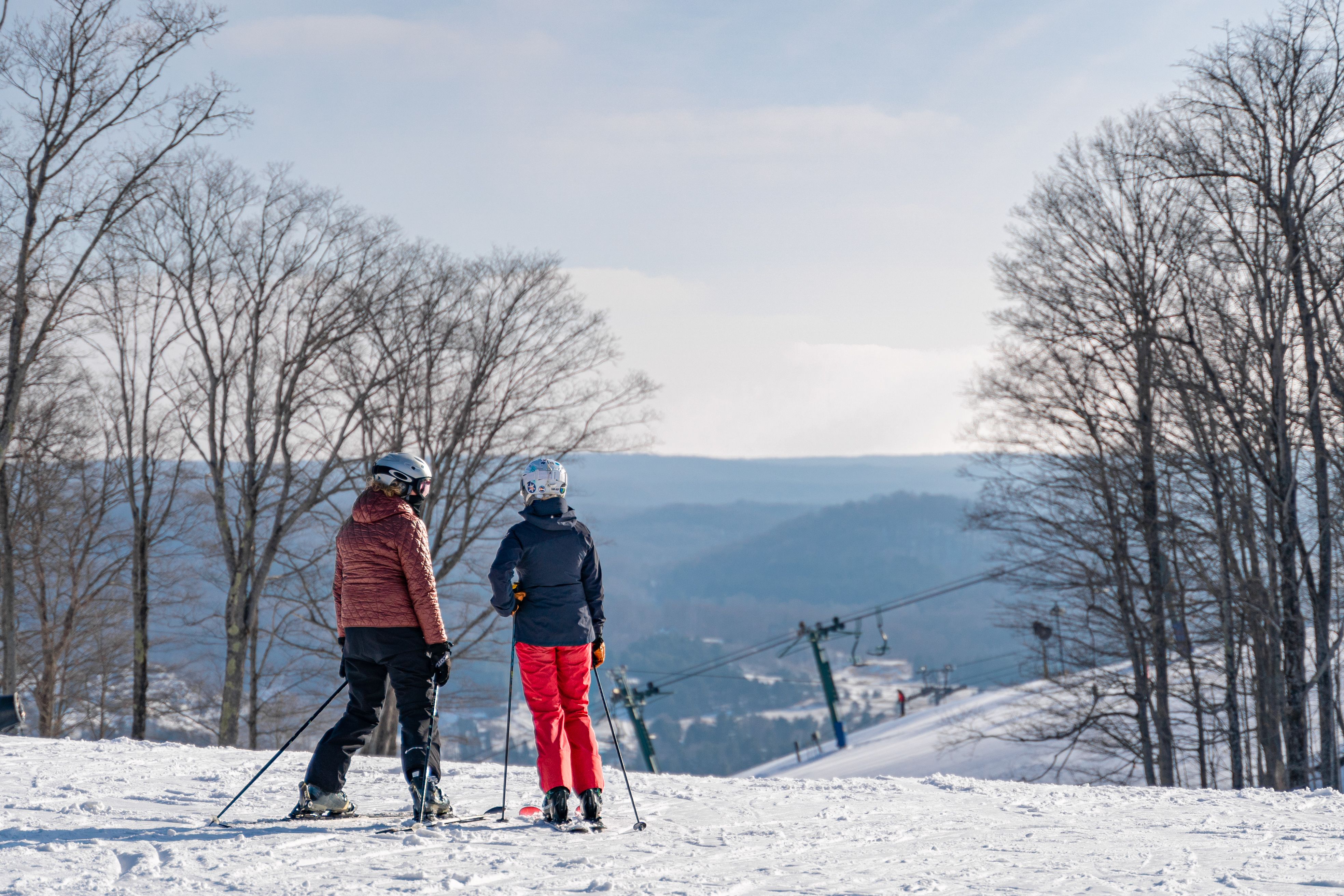 Ski couple looks out at winter slope and valley view