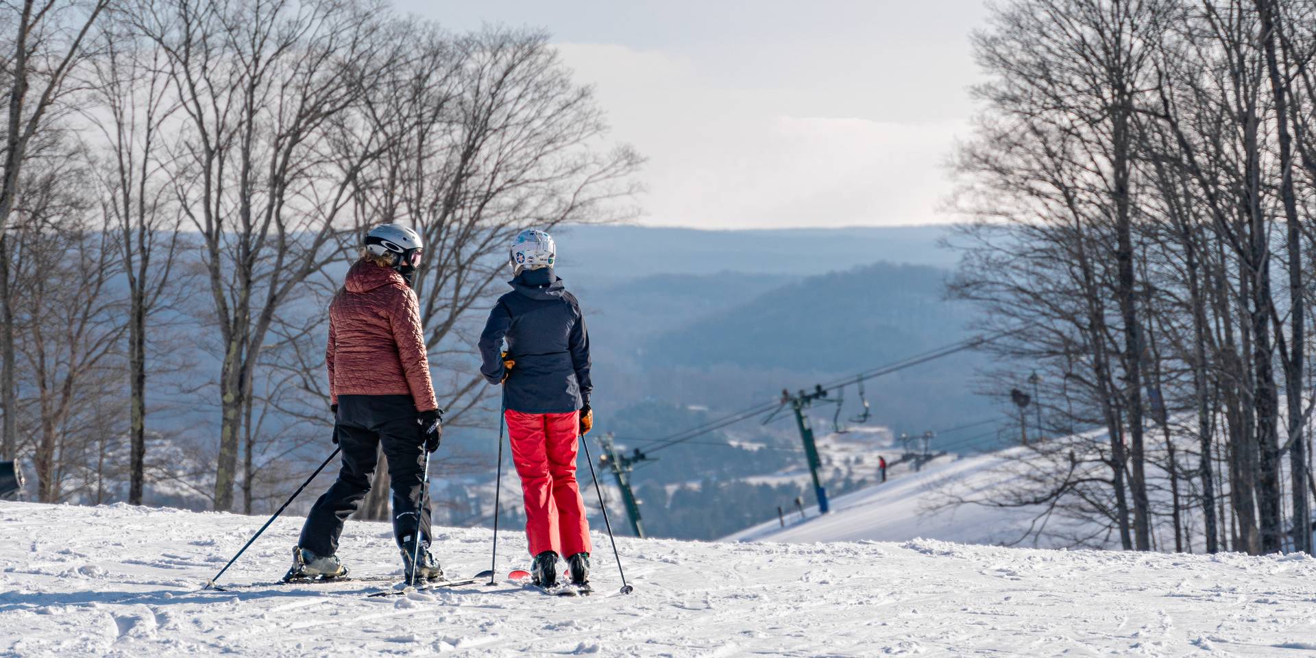 Ski couple looks out at winter slope and valley view