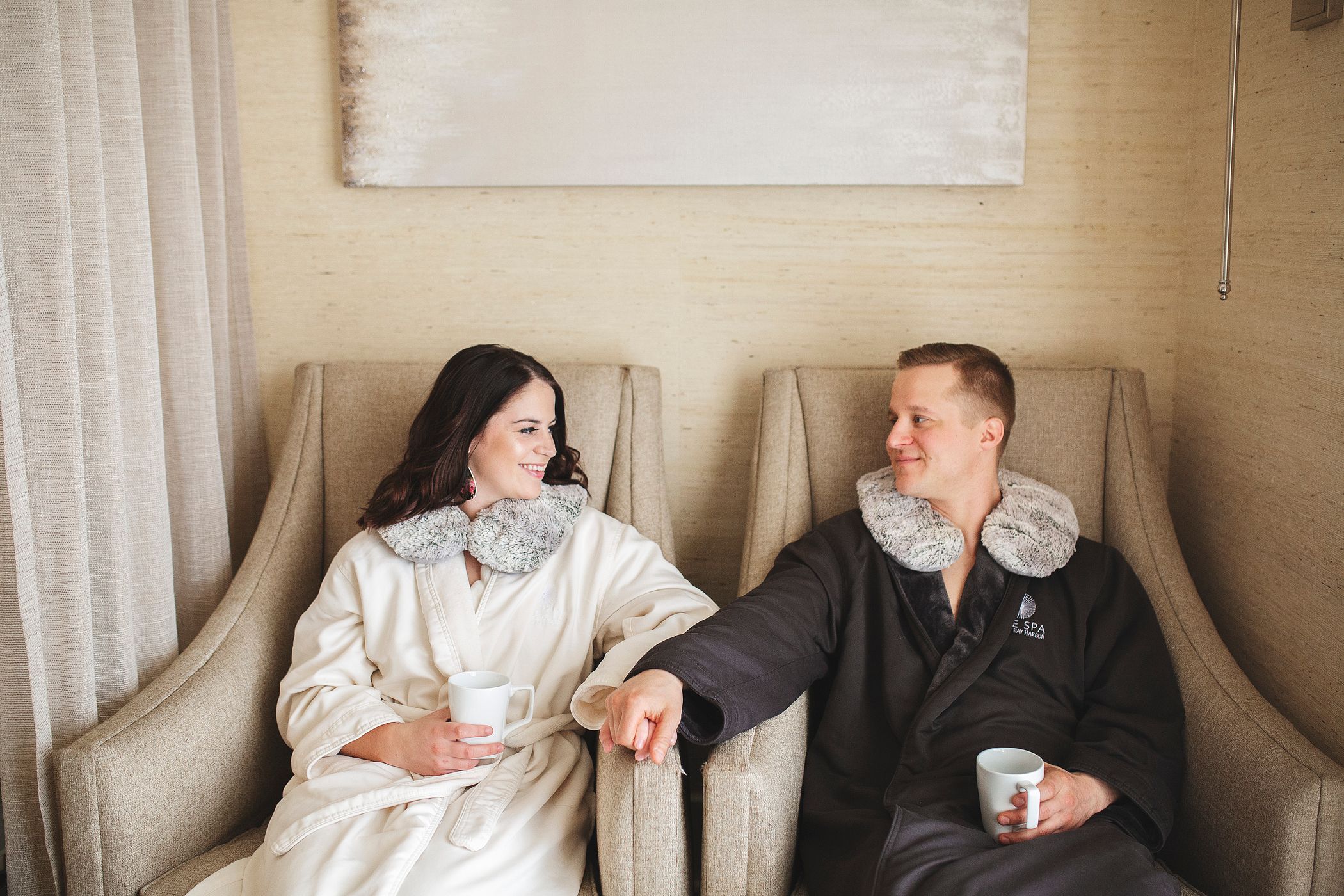 Young couple holds hands and smiles in spa robes at The Spa