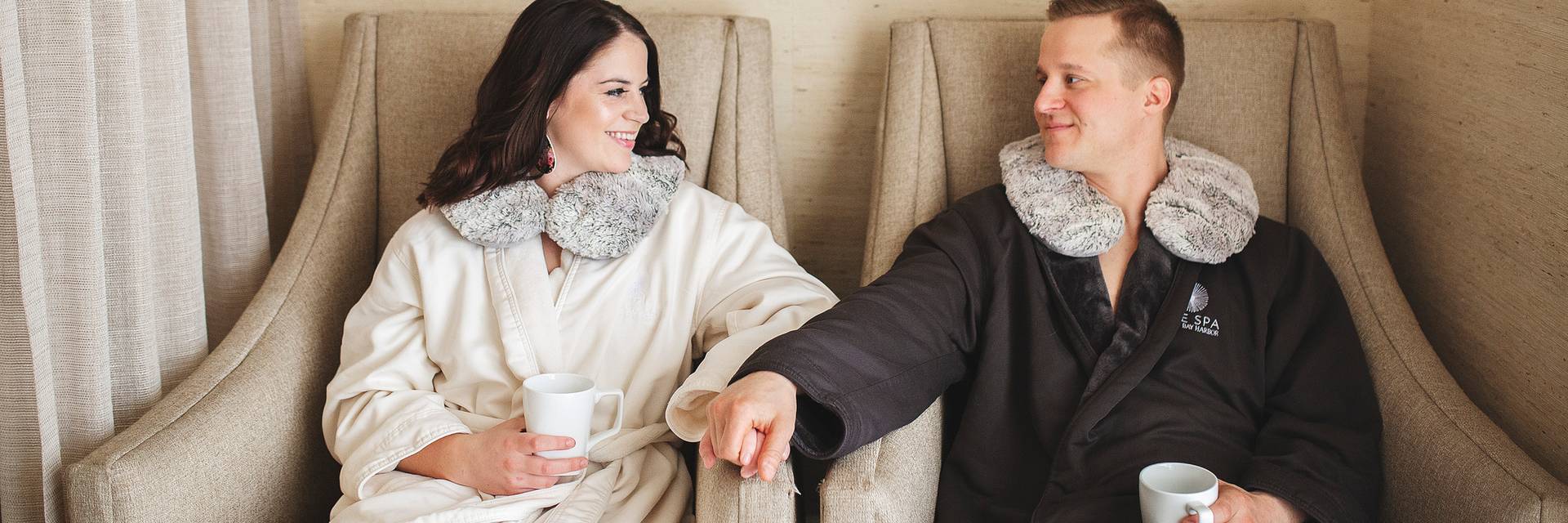 Young couple holds hands and smiles in spa robes at The Spa
