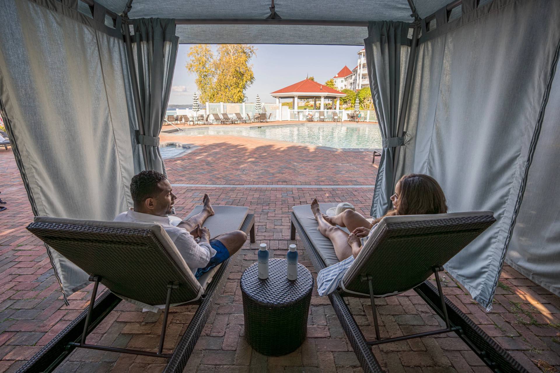 Back view of smiling couple relaxing on Poolside Cabana loungers, Inn at Bay Harbor pool