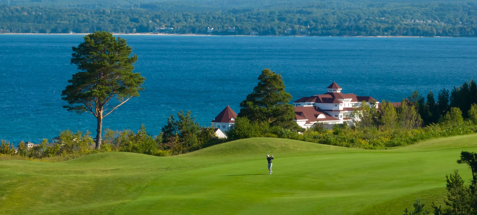 Golfer swings on Crooked Tree Golf Club course, overlooking Lake Michigan
