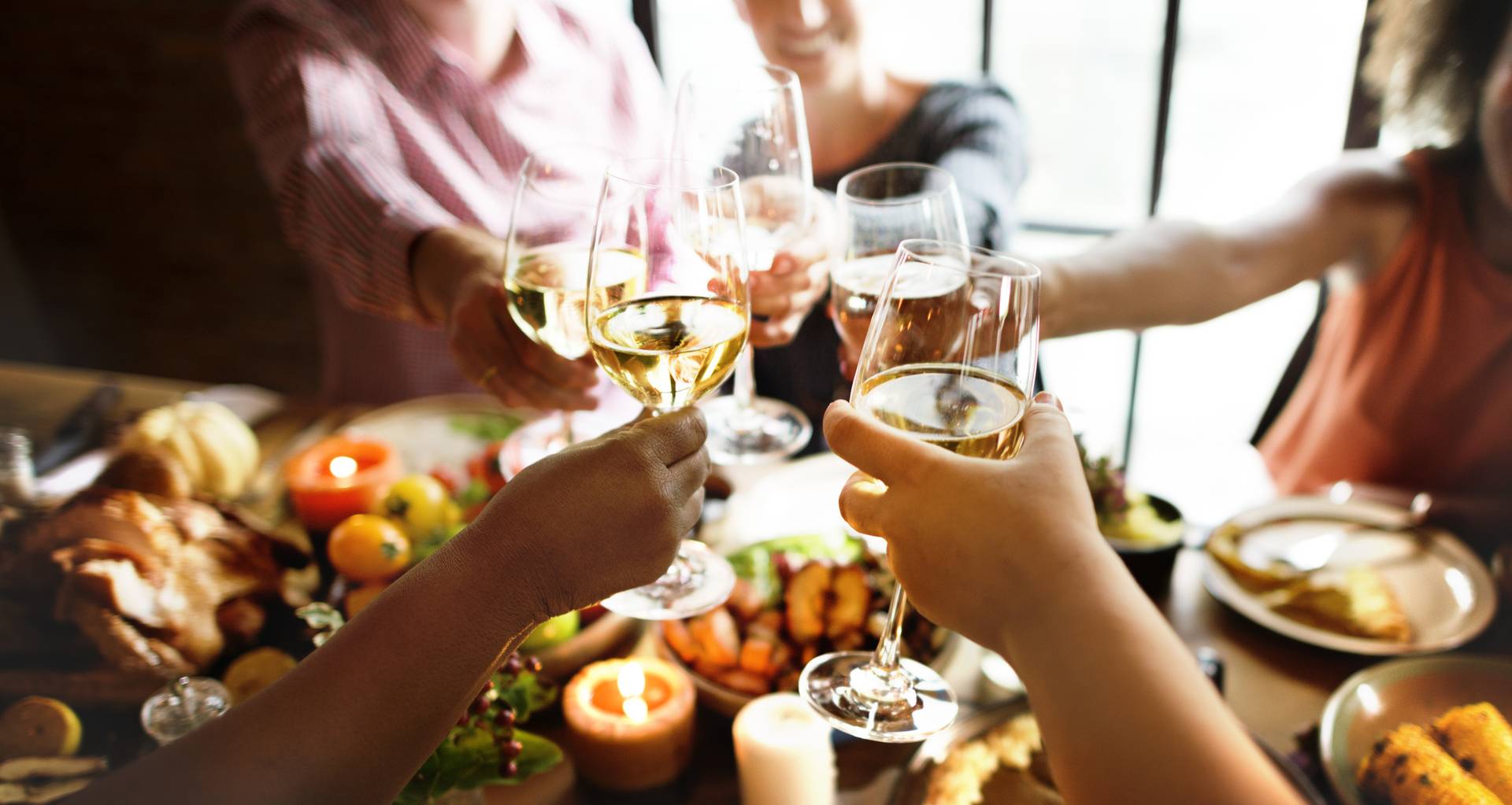 White wine glasses clink over Thanksgiving table