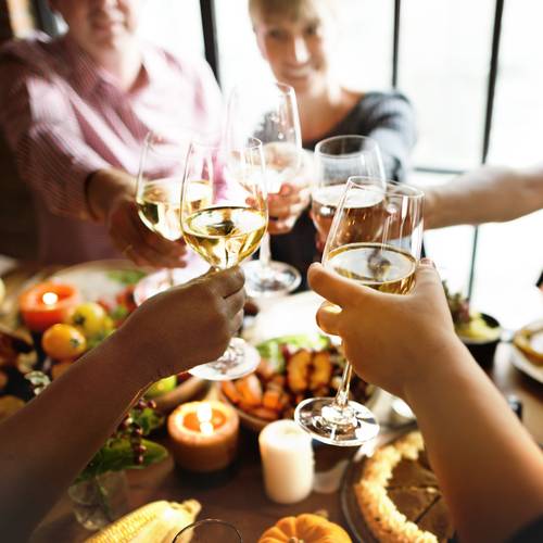 White wine glasses clink over Thanksgiving table