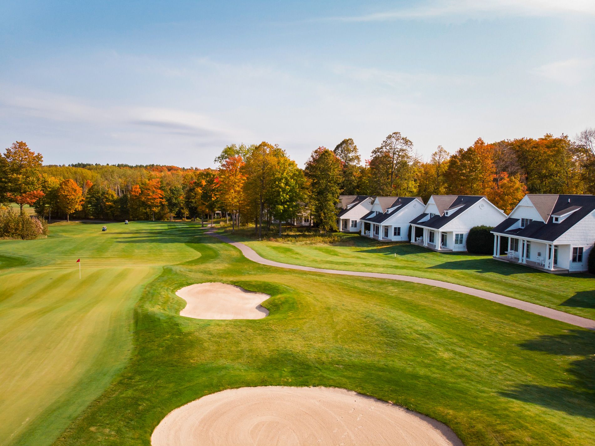 Fairway, sand bunkers of autumn golf course lined by white cottages, Crooked Tree Golf Club